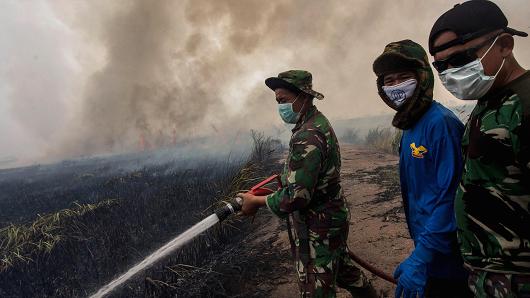 Indonesian soldiers extinguish the fire on burned peatland and fields on October 2, 2015 in Palembang, South Sumatra, Indonesia.